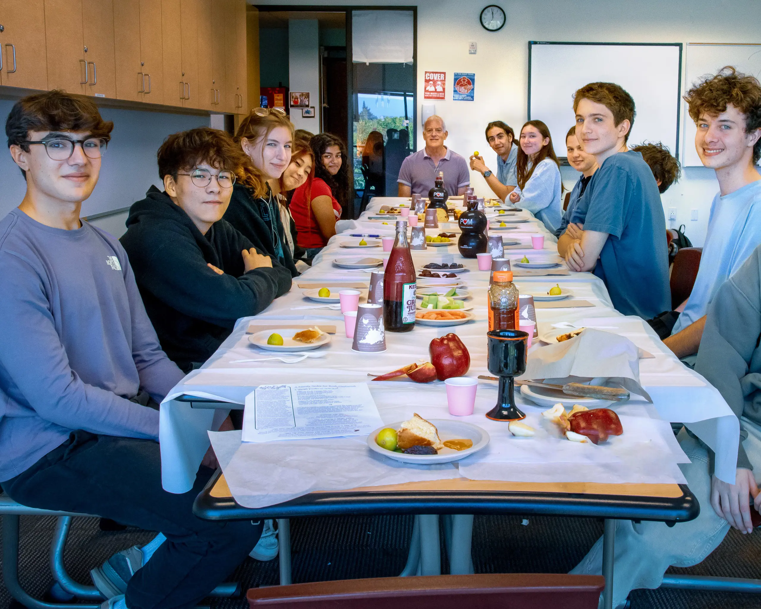 A long table filled with food, surrounded by a group of people engaged  in conversation and sharing a meal.