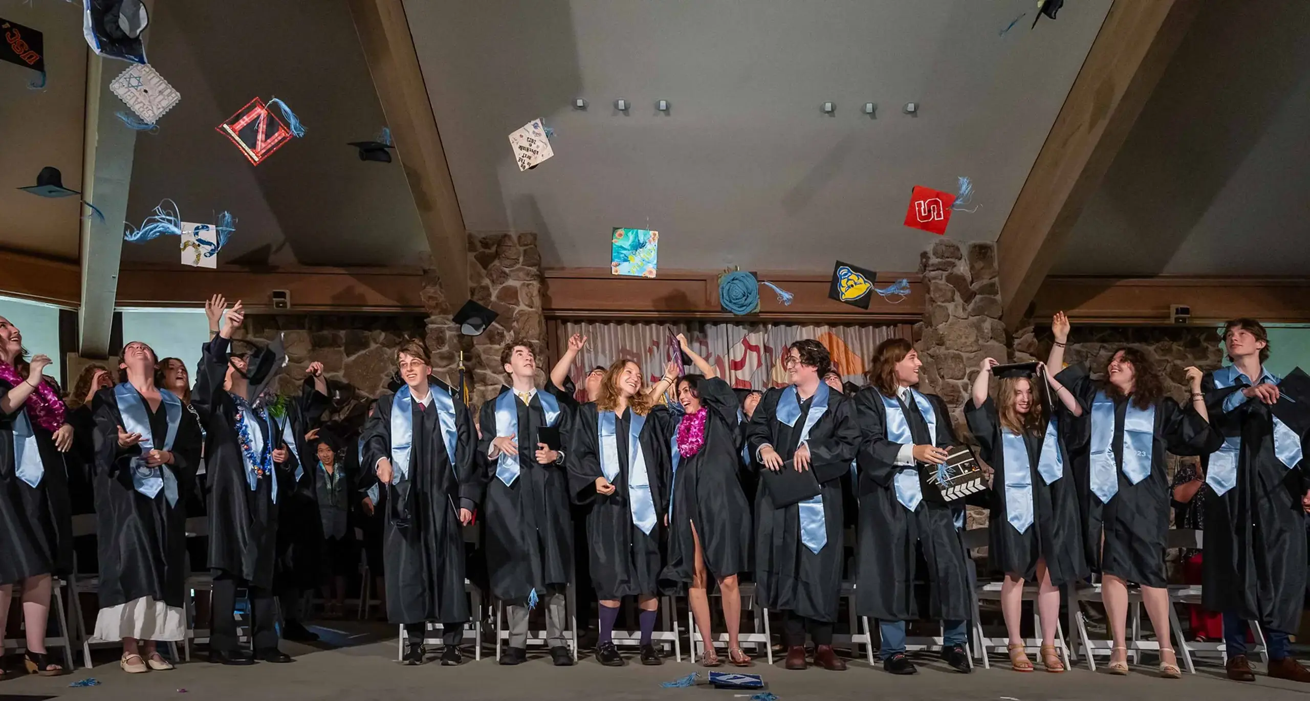 A group of graduates wearing caps and gowns, smiling and celebrating their graduation day together.