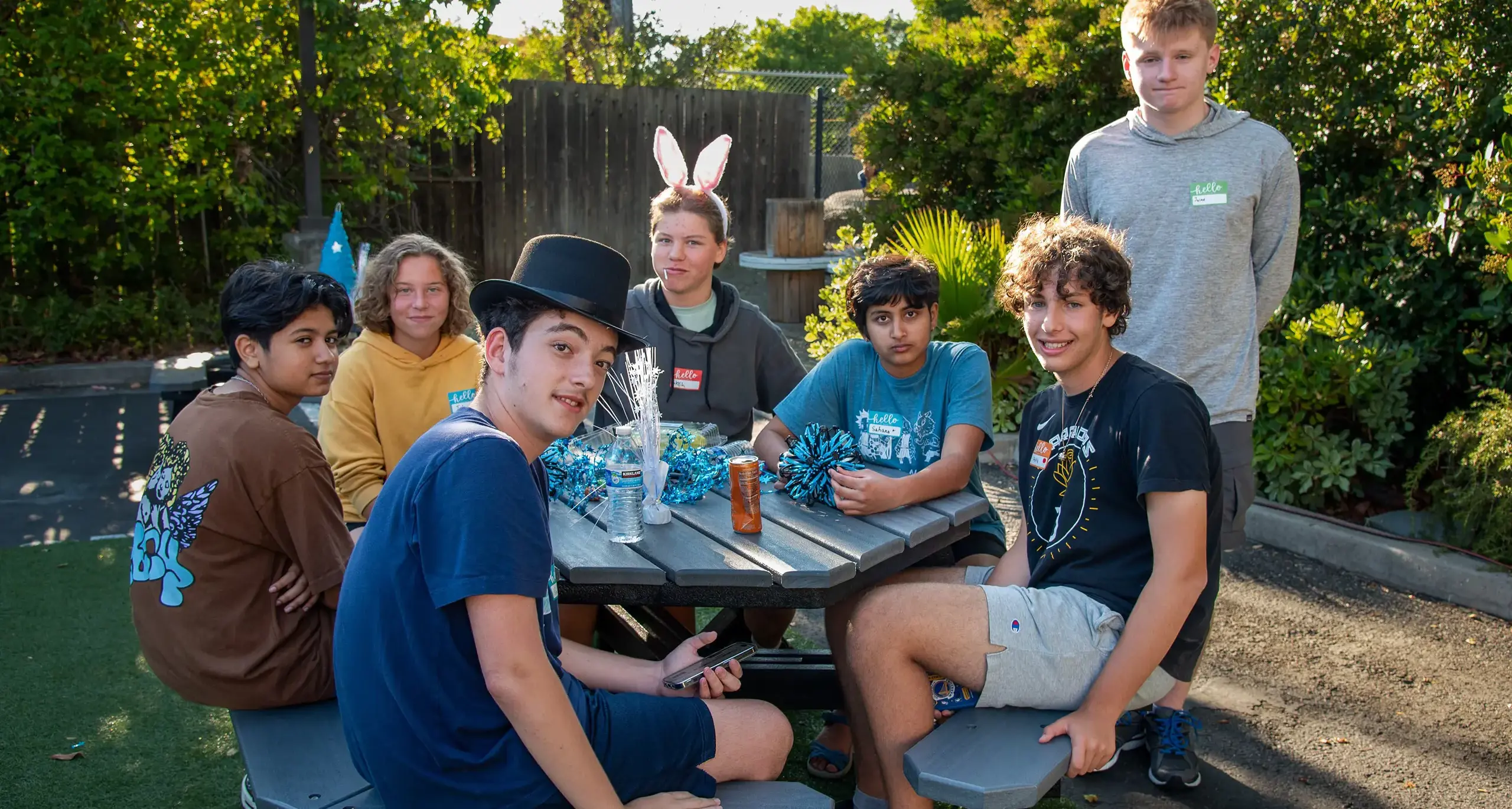 A group of diverse individuals sitting together outside smiling, engaged  in conversation and interaction.