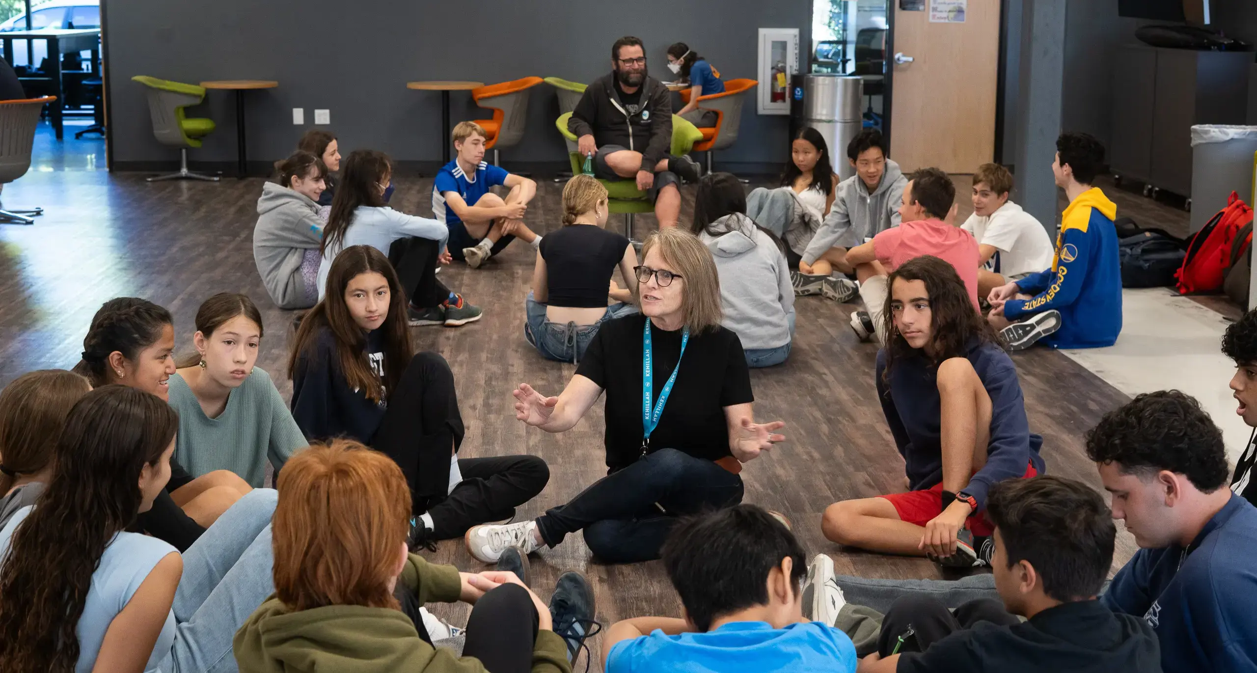 Students Sat in Circle with Teacher Discussing Lesson